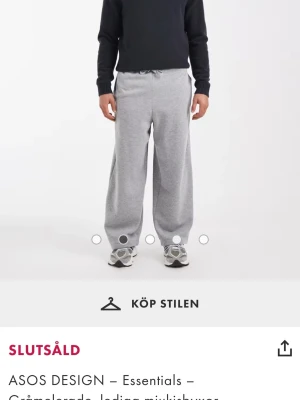 Grå loose mjukisbyxor ASOS DESIGN - Gråmelerade mjukisbyxor från ASOS DESIGN med loose passform och snörning i midjan. Byxorna har breda ben och är tillverkade i mjukt bomullsmaterial som är perfekt för chill dagar. Klassisk design med elastiska muddar vid benslut.