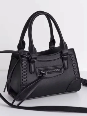 Svart handväska med detaljer - Snygg svart handväska i konstläder med flätade detaljer på sidorna och en liten dragkedjeficka framtill. Väskan har både handtag och en lång axelrem, perfekt för att bära på olika sätt. Stängs med dragkedja och har dekorativa remmar framtill.