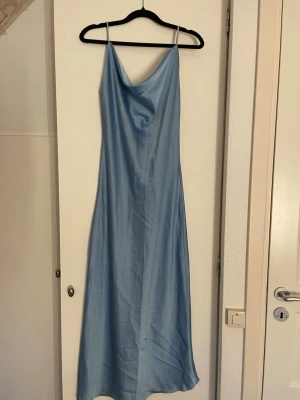 Ljusblå balklänning - Säljer en ljusblå långklänning med tunna axelband och draperad urringning. Klänningen har är fin lite åtsittande passform. Den säljs pågrund av att den är något kort på mig, som är 173. Men storleken passar, jag bär S/M. Materialet är satin. Priset kan diskuteras 
