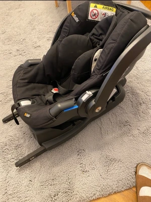 Svart babyskydd BeSafe med bas - Säljer ett svart babyskydd från BeSafe med tillhörande bas. Sätet har mjuk stoppning, bärhandtag och tydliga säkerhetsbälten. Basen har enkla instruktioner och fästen för smidig installation i bilen. Perfekt för att transportera små barn säkert.