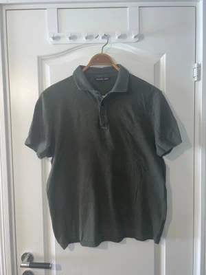 Grön pikétröja från Michael Kors - Michael Kors pikétröja i mörkgrön färg, storlek M. Tröjan är i mycket fint skick och endast använd några få gånger. En stilren och bekväm modell som passar bra till både vardag och lite mer uppklädda tillfällen. Finns att hämta i Södertälje eller Örebro.