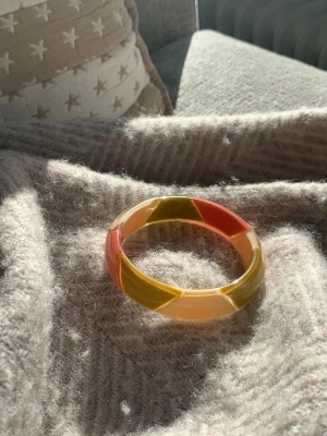 Färgglatt vintage armband  - Snyggt armband med geometriska fält i orange, gult och beige. Armbandet har en bred, rund form och en cool retrovibe som sticker ut. Perfekt accessoar för dig som gillar färg och unika detaljer.