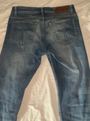 Blåa tiger of Sweden slim jeans 28/32 - Pris kan diskuteras. Snygga blå slim fit jeans med klassiska bakfickor. Jeansen har normal midja och smal passform hela vägen ner. Perfekta för en avslappnad och trendig look. Materialet är denim i bomull med lite stretch för extra komfort.