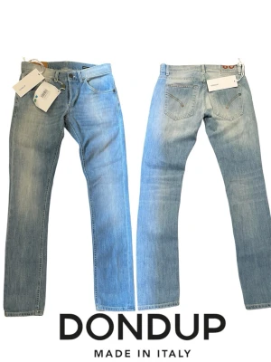 Ljusblå raka jeans från Dondup - Säljer ett par ljusblå jeans från Dondup. Helt nya med rak passform och klassisk femficksdesign. Jeansen är tillverkade i mjuk denim och har snygga slitningar för en avslappnad look. Perfekta för dig som gillar italiensk design och stil.Ett par sprillans nya Dondup jeans. Riktigt snygg blåfärg!   Midja 37cm ( bara rakt över)   Innerbenslängd 75 cm.   Benöppning 14 cm    #Rayban #RalphLauren #Rayban #maison #phillipemodel #open #valentino #massimo #jeans #Boyfriend #Nudie #goldengoose  #Mitchella