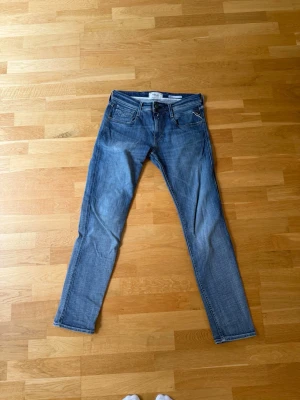 Blå slim fit jeans från Replay - Snygga blå slim fit jeans från Replay med klassisk femficksdesign och dragkedjegylf. Jeansen har en något tvättad look och raka ben. Perfekta för en avslappnad och trendig stil.