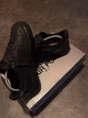 Nike x space jam Airforce 1 - Säljer ett par helsvarta Nike Air Force 1 sneakers med klassisk låg siluett. Skorna har ovandel i läder och textil, perforerade detaljer på tån och en robust sula. Perfekta för dig som gillar stilrena och tidlösa sneakers.