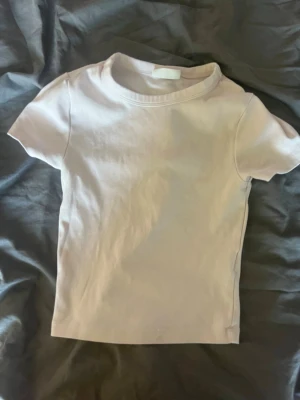 Ljusrosa topp från Gina Tricot - Enkel och stilren ljusrosa topp från Gina Tricot, modell Basically Basic. Toppen har rund halsringning och korta ärmar. Perfekt att matcha med jeans eller kjol för en clean look. Tillverkad i mjukt bomullsmaterial.