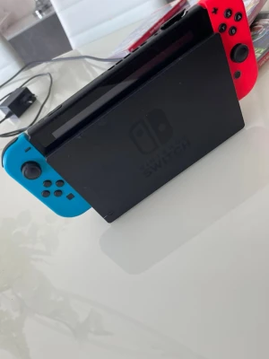 Nintendo Switch med spel och tillbehör - Nintendo Switch med blå och röd Joy-Con, dockningsstation och handkontrollshållare. Inkluderar fem populära spel: Luigi's Mansion 3, Super Smash Bros Ultimate, Minecraft, Mario Kart 8 Deluxe och Super Mario Odyssey. Perfekt för gaming och multiplayer. Kan diskutera priset 