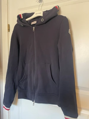  Moncler hoodie - Säljer nu min moncler hoodie som är sparsamt använd , den har tyvärr inga snören i luvan och har fått sig ett hål i ena ärmen men är snyggt lagat , vet inte riktigt ett pris så kom med bud ( ser ut och vara solblekt men är den är tvättad och tappat piggment )
