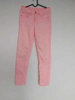 Ljusrosa skinny jeans - Snygga ljusrosa skinny jeans med klassisk femficksdesign och låg midja. Jeansen har smal passform och är perfekta för dig som vill sticka ut med färg. Materialet är mjukt och stretchigt för extra komfort.