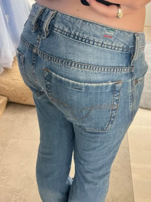 Bootcut diesel jeans  - Ljusblå jeans från Diesel med klassisk bootcut passform och femficksdesign. Jeansen har tydliga sömmar på bakfickorna och är tillverkade i slitstarkt denim-material. Perfekta för dig som gillar en tidlös och avslappnad look.