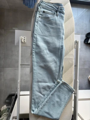 Ljusblå Lee jeans med rak passform - Säljer ett par ljusblå jeans från Lee med klassisk femficksdesign och rak passform. Jeansen har bälteshällor, dragkedjegylf och Lee-logga på linningen. Perfekta för en avslappnad och trendig look. Storlek: W29 & L33