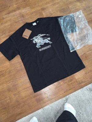 Svart Burberry t-shirt med tryck - Snygg svart t-shirt från Burberry, klassisk rund hals och avslappnad passform. Tillverkad i mjuk bomull för skön känsla. quality🔥🔥🔥🔥
