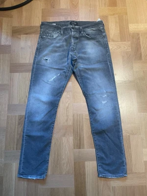 Slim jeans från Jack&jones  - Säljer ett par gråa slim jeans med slitningar och distressed detaljer på framsidan från jack&jones. Säljer dessa för 499kr. Jeansen har klassisk femficksdesign och normal midja. Perfekta för en avslappnad och trendig look.