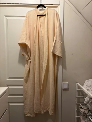 Abaya - Jag säljer en lång abaya i one size storlek, jättefin gul beige underton på den passar perfekt till allt.💛
