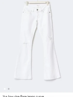 Gina young jeans  - Snygga vita jeans med låg midja och utsvängda ben. Jeansen har slitna detaljer på låren och cool broderad bakficka. Perfekta för en trendig och avslappnad stil. Tillverkade i denim med klassiska fickor och bälteshällor.