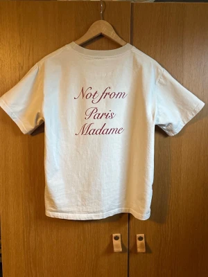 Drôle de monsieur t-shirt - Vit t-shirt i bomull med trycket 'Not from Paris Madame' i röd text både fram och bak. Klassisk passform med rund hals och korta ärmar. Perfekt för en avslappnad och trendig stil.