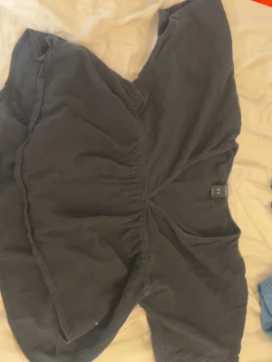 Svart blus från Lindex - Snygg svart blus från lindex med volang nertill och lös passform. Blusen har korta ärmar och är tillverkad i ett mjukt, vävt tyg som ger en luftig känsla. Perfekt att styla med jeans eller kjol för en trendig look.