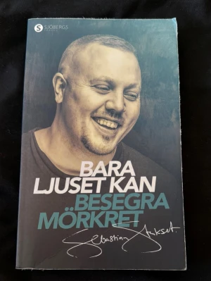 Bara ljuset kan besegra mörkret - En inspirerande skönlitterär bok med titeln 'Bara ljuset kan besegra mörkret' från Sjöbergs. Omslaget är blågrönt med vit och blå text samt ett porträttfoto. Perfekt för dig som gillar starka berättelser och personliga resor.