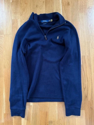 Polo Ralph Lauren tröja Quarter-Zip - Blå bomullströja från Ralph Lauren i stl S med kort dragkedja i halsen. Liten broderad logga på bröstet.     Tröjan har inbyggd QR-kod för autentisering som verifierar att den är 100% äkta.     Estate-Rib Quarter-Zip Pullover Navy   Tröja Blå dragkedja krage   100% bomull      Nypris: 2200 kr      Kan även skickas!😃