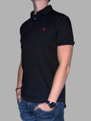 Svart pikétröja från Ralph Lauren - 🔹 Märke: Ralph Lauren 🔹 Modell: Pikétröja  🔹 Storlek: M 🔹 Färg: Svart 🔹 Skick: Fint skick, lite sliten i sömmarna men inget som syns vid användning. 🔹 Passform: Custom fit 🔹 Pris: 349kr  ✅ 100% äkta ✅ Snabb frakt ✅ Fler bilder/video finns vid intresse ✅ Stilren och lättmatchad