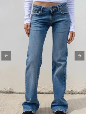 Lågmidjade bootcut jeans  - Säljer ett par klassiska blå bootcut jeans från Lee med fem fickor och normalhög midja. Jeansen har en snygg tvätt och subtila slitningar, samt Lee-logga på bakfickan. Tillverkade i mjuk denim med lite stretch för skön passform.