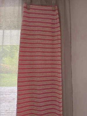 Rosa och vit randig långkjol - Säljer en långkjol med rosa och vita ränder. Kjolen har en rak passform och är stickad i ett mjukt material som känns både trendigt och bekvämt. Perfekt för dig som gillar en söt och avslappnad stil.