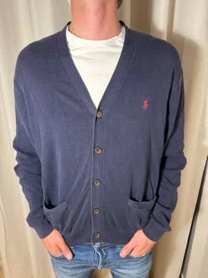 Ralph Lauren cardigan - Hallö! Nu säljer vi denna sjukt mysiga Ralph Lauren cardigan i 100% bomull för endast 349kr medans nypriset på en sån kostar hela 2786kr. Storlek är L. Hör av er vid frågor och funderingar. Pris kan sänkas vid snabb och smidig affär💙 // Studio II Resell 