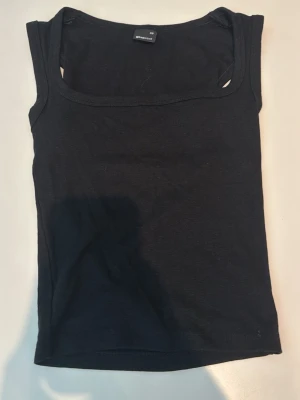 Svart linnetopp från Gina Tricot - En enkel och stilren svart linnetopp från Gina Tricot. Toppen är ärmlös med rundad halsringning och tillverkad i mjukt bomullsmaterial. Perfekt att matcha med jeans eller kjol för en clean look.