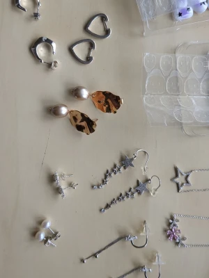 Mixade örhängen, halsband osv - Säljer ett set med flera olika örhängen i både silver- och guldfärg, även mycket annat. Säljer  två halsband i silverfärg med tillhörande örhängen. Även två olika håraccessoarer med fina detaljer. Två par örhängen längst till vänster är från KappAhl och snöflingorna är från glitter. Pris kan diskuteras:)