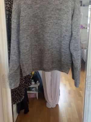 Grå stickad tröja från ICHI - Mysig grå stickad tröja från ICHI med rund halsringning och ribbade muddar vid ärmslut och nederkant. Perfekt för lager på lager och enkel att matcha med olika outfits. Klassisk modell i mjukt material. Men sticks litegrann i matrialet