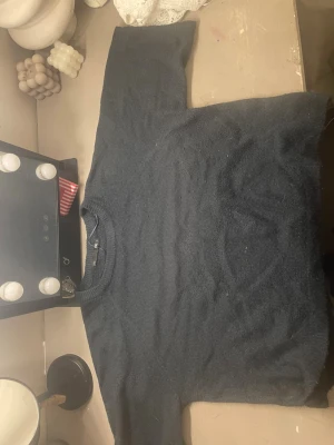 Mörkblå stickad tröja från Monki - Mysig mörkblå stickad tröja från Monki med rund halsringning och ribbade muddar. Tröjan har en enkel, klassisk design och är perfekt för lager på lager. Materialet är mjukt och behagligt, vilket gör den skön att bära under kyliga dagar.