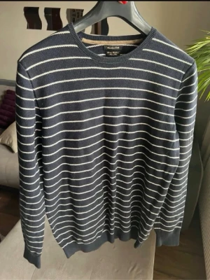 Marinblå randig tröja Massimo Dutti - Stickad marinblå tröja från Massimo Dutti med tunna vita horisontella ränder. Rund halsringning och ribbade muddar vid ärmslut och nederkant. Tillverkad i en mjuk blandning av bomull och kashmir för extra komfort.