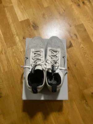 Nike Vita VaporMax sneakers - Nike VaporMax sneakers i vitt med svart swoosh och detaljer. Ovandelen är i stickad mesh för skön andningsförmåga och sulan är genomskinlig med den klassiska VaporMax-looken. Skorna har vita snören och pull tab bak för enkel påtagning.