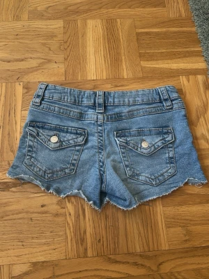 Ljusblå jeansshorts Gina Tricot - Säljer ett par ljusblå,lågmidjade jeansshorts med råa kanter och klassisk femficksdesign från Gina tricot Young.💕💕I mycket bra skick💕💕Nypris är ca 260 kr, jag säljer dem för 75 kr💕💕Hör av er vid intresse💕💕