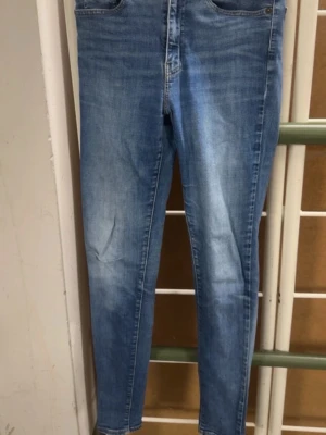 Ljusblå skinny jeans från Levi's - Säljer ett par ljusblå skinny jeans från Levi's med klassisk femficksdesign och snygga slitningar. Jeansen har hög midja och smal passform hela vägen ner. Tillverkade i stretchigt denim för extra komfort. Perfekta till sneakers eller boots. Pris kan diskuteras. Har en split i knät 