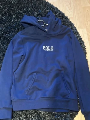 Mörkblå hoodie  Polo Ralph Lauren - Snygg mörkblå hoodie från Polo Ralph Lauren med vit logga på bröstet. Klassisk känguruficka framtill och huva. Storlek Barn L 14/16 år. Är i bra skick.