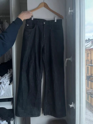 Loose fit svarta jeans Cheap Monday - Säljer ett par svarta loose fit jeans från Cheap Monday i modellen Looser Regular Waist. Jeansen har raka, vida ben och klassisk femficksdesign. Färgen är Extra Black Rins och materialet är denim i bomull. Perfekta för en avslappnad och trendig streetwear-look.