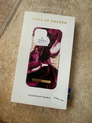 iDeal of Sweden Golden Ruby Marble skal - Snyggt mobilskal till iPhone 13 Pro från iDeal of Sweden i designen Golden Ruby Marble. Skalets mönster har en mix av lila, svart och guldiga toner som ger en lyxig marmorkänsla. Tillverkat i hårdplast för bra skydd och stilren look.