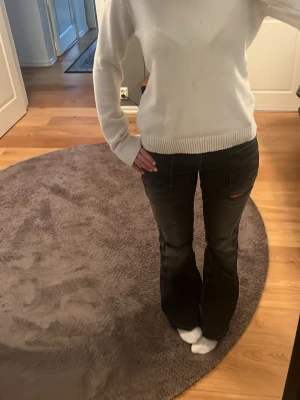 Vit ribbad stickad tröja - Klassisk vit stickad tröja med ribbade muddar vid ärmslut och nederkant. Tröjan har en enkel, rak passform och rund halsringning. Perfekt att matcha med jeans eller kjol för en clean look. En fläck på magen💕