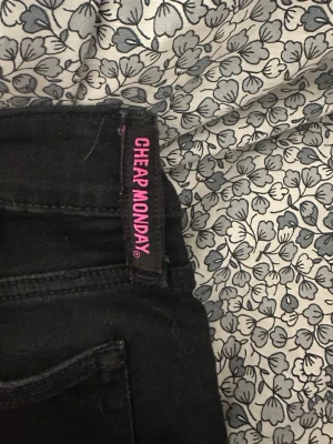 Svarta cheap Monday jeans - Svarta lågmidjade bootcut jeans. Rosa lappen bak är borttagen av tidigare ägare( se bild 4)Storlek 26.32. Har själv aldrig använt men tidigare ägare har använt enstaka gång