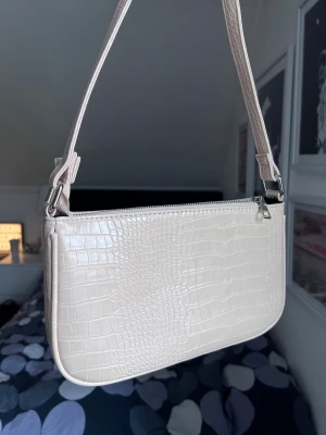 Beige y2k väska i krokodilmönster - Snygg beige axelväska med krokodilmönster och dragkedja. Väskan har ett stort rymligt fack och tre mindre 🌸 Aldig använd! Storlek: 27x16cm