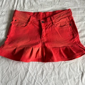 Röd volangkjol i denim - Färgen är som på bild 1 och 2, bild 3 och fyra är tagna i annat ljus därav färgskillnad. Midjemått rakt över: 39 cm