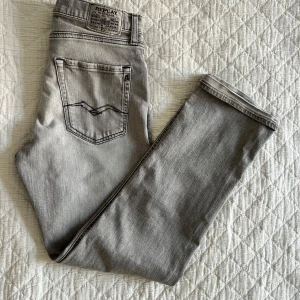 Replay Thad jeans - Replay jeans modell Thad i grå nyans, storlek 160. Jeansen har raka ben, normalhög midja och gylfen består av knapp och dragkedja. 