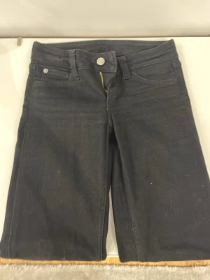 Svarta jeans med dragkedja weekday  - Säljer ett par svarta denimjeabs Från weekday  med klassisk femficksdesign och synlig dragkedja fram. Shortsen har normal passform och midja, samt raka ben. Perfekta för en avslappnad och cool stil.