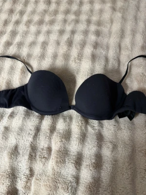 Svart push-up bh med bygel - Snygg svart vanlig bh med bygel och vadderade kupor. Axelbanden är justerbara och modellen ger bra stöd och form. Perfekt under toppar och klänningar där du vill ha extra lyft. Materialet känns mjukt och bekvämt mot huden.