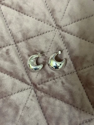 Chunky silverfärgade hoops örhängen - Säljer ett par chunky hoops örhängen i silverfärg med rundad, tjock design. De har en blank, spegelblank yta och stiftlås. Perfekta för dig som gillar statement-smycken med modern känsla.