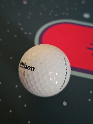 Wilson golfboll vit - Säljer en vit golfboll från Wilson med texten '1 X Distance' och siffran 4 tryckt på. Klassisk rund form med dimple-mönster för bättre flyg och kontroll. Perfekt för dig som vill ha en pålitlig boll till golfbanan.