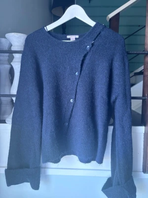 Mörkblå stickad kofta med knappar - Mysig mörkblå stickad kofta med sned knäppning framtill och långa ärmar med breda muddar. Aldrig använt. Skriv för fler bilder. Tvättar såklart innan jag postar❣️