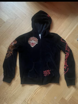 Svart vintage hoodie från ed Hardy  - En vintage svart hoodie från ed hardy i sammet. Märkt XL men är mer som en S. Fint skick enda defekten är att dragkedja ”pluppen” ramlat av. Men dragkedjan fungerar ändå som vanligt